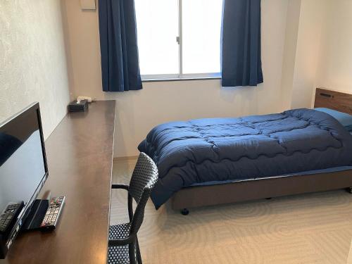 a bedroom with a bed and a desk with a computer at HOTEL PAiKAJi in Ishigaki Island