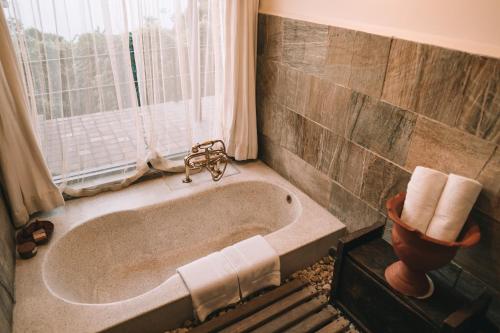 une baignoire dans une salle de bain avec une fenêtre dans l'établissement Dwarika's Sanctuary, à Dhulikhel