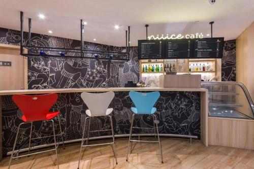 a bar with three stools in front of a counter at Ibis Xinzhou Qiyi RD in Xinzhou Zhan