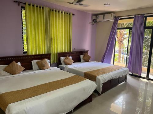 deux lits dans une chambre avec des rideaux violets et verts dans l'établissement SAHAY VILLA RESORT, à Durbate