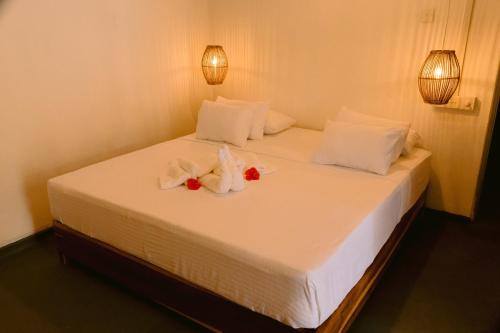 a bed with white sheets and flowers on it at Diviya Bungalow and Cantina in Matara