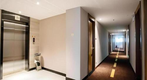 einen Flur mit weißen Wänden und einen langen Flur mit Türen in der Unterkunft JTOUR Inn Yulin Railway Station Industrial Products Market in Yulin