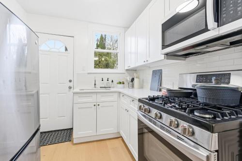 a kitchen with white cabinets and a stove top oven at Hamilton-15 mins to EWR, 20 mins PATH to NYC in Harrison