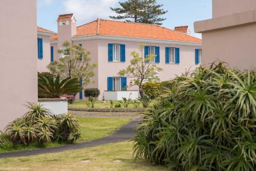 a house with blue windows and plants in a yard at Azoris Faial Garden – Resort Hotel in Horta
