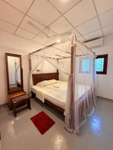 1 dormitorio con cama con dosel y alfombra roja en Dushan's House, en Ahangama