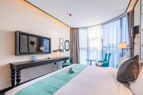 ein Hotelzimmer mit Bett, Schreibtisch und Fernseher in der Unterkunft Xana Hotelle Nanchang Tengwang Pavilion Qingshan Road Metro Station in Nanchang County