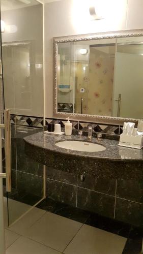 a bathroom with a sink and a mirror at Wonderful Hall Hotel in Xinzhuang