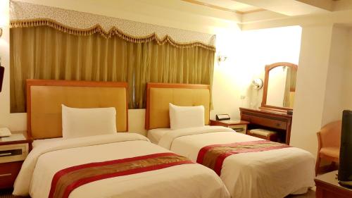 a hotel room with two beds and a mirror at Wonderful Hall Hotel in Xinzhuang
