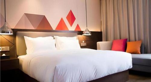 a hotel room with a large white bed with colorful pillows at Borrman Hotel Huanggang Wuxue Yuhu Road in Wuxue