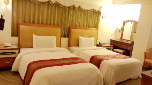 a hotel room with two beds and a mirror at Wonderful Hall Hotel in Xinzhuang