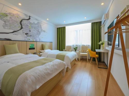 um quarto de hotel com duas camas e uma escrivaninha em Vatica Hotel Huangshan South Gate Terminal Station em Área Cénica das Montanhas Huangshan