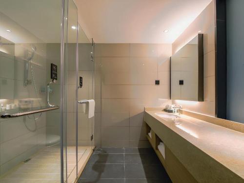 a bathroom with a glass shower and a sink at City Comfort Inn Shiyan High-speed Railway Wanda Plaza in Shiyan