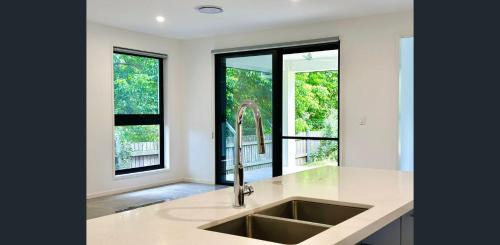 eine Küche mit einem Waschbecken und einigen Fenstern in der Unterkunft Sunnybank Station 5B Family Stay in Brisbane
