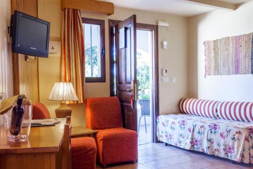 a hotel room with a bed and a desk and a tv at Hotel Alcadima in Lanjarón