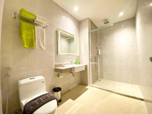 une salle de bain blanche avec toilettes et douche dans l'établissement MaxOneHotels at Kota Harapan Indah-Bekasi, à Bekasi