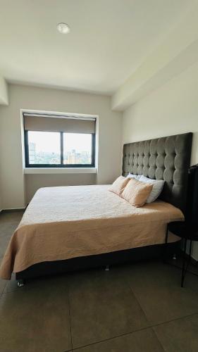 a bedroom with a large bed with a large window at Departamento Lafayette, cerca de Chapultepec, CAS, Minerva in Guadalajara