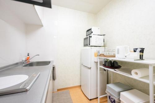 eine kleine Küche mit einem weißen Kühlschrank und einer Spüle in der Unterkunft 瓦の灯 in Takamatsu