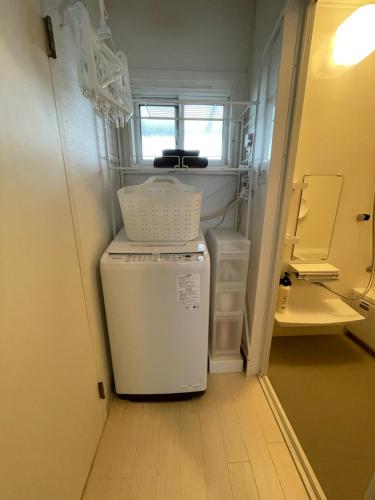a small white refrigerator in a small room at 一棟貸し宿ゲストハウスサンク in Masuda