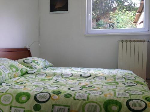 a bed with a quilt on it with a window at Apartma R Sport in Tolmin
