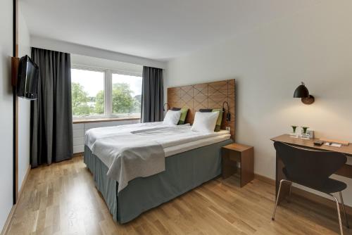 a bedroom with a bed and a desk and a window at Quality Hotel Grand, Borås in Borås