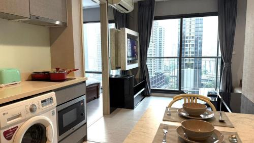 a kitchen with a washing machine and a table with chairs at Modern Bangkok Apartment Train Access in Bangkok