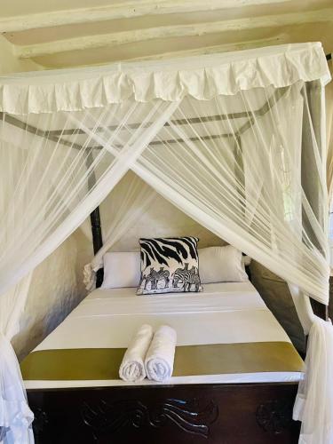 un letto a baldacchino con tende bianche e cuscini di 3 bedroom own compound house a Malindi