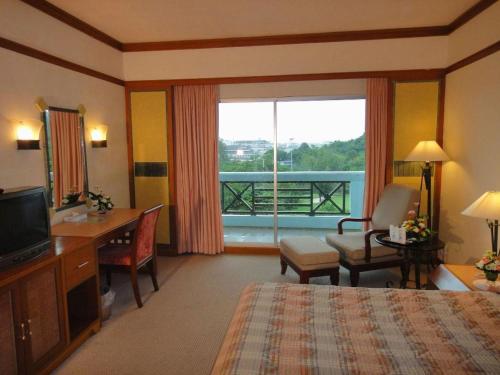 a hotel room with a bed and a desk and a window at BP Samila Beach Hotel & Resort in Songkhla