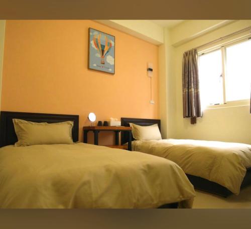 une chambre d'hôtel avec deux lits et une fenêtre dans l'établissement 拼圖休閒民宿, à Hsia-pu-hsia