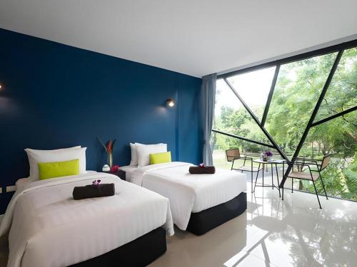 zwei Betten in einem Zimmer mit großem Fenster in der Unterkunft The Forest Home Resort in Ban Dong
