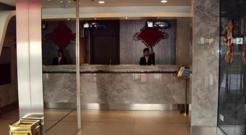 deux personnes debout à un comptoir dans un hall dans l'établissement JinJiang Inn Datong Pingchengqiao, à Datong