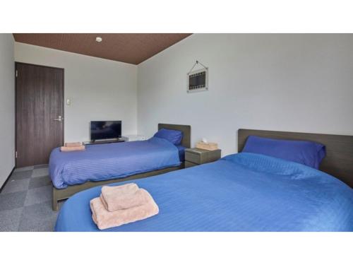 um quarto com 2 camas com lençóis azuis e uma televisão em AMA TERRACE - Vacation STAY 31145v em Amami