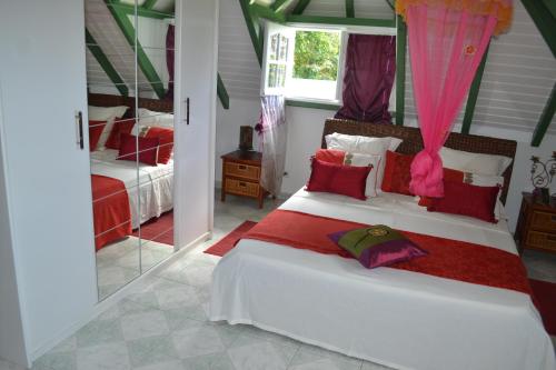 - une chambre avec un grand lit blanc et des oreillers roses dans l'établissement La Nicotoria HAUT DE VILLA T4, à Deshaies