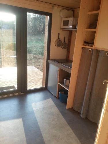 a small kitchen with a sliding door to a deck at Domaine de l'Ours / Camping Lodge in Saint-Urcize
