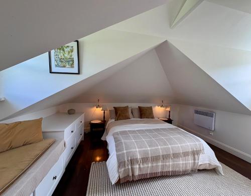 une chambre mansardée avec un lit et un canapé dans l'établissement Oakchester Cottage on Bruny Island, à Killora