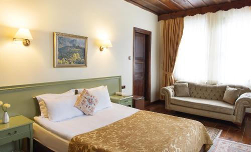 a bedroom with a bed with a couch and a chair at Uğurlu Konakları in Kastamonu