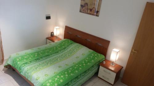 a bedroom with a green bed with two night stands at Solaire Valentano in Valentano