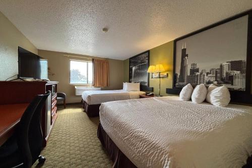 a hotel room with two beds and a flat screen tv at Super 8 by Wyndham Pontiac in Pontiac