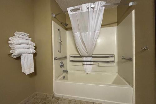 a bathroom with a tub and a shower with towels at Super 8 by Wyndham Pontiac in Pontiac