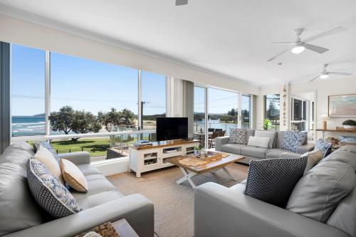 a living room with couches and a tv and windows at The Rotunda, Gerroa in Gerroa