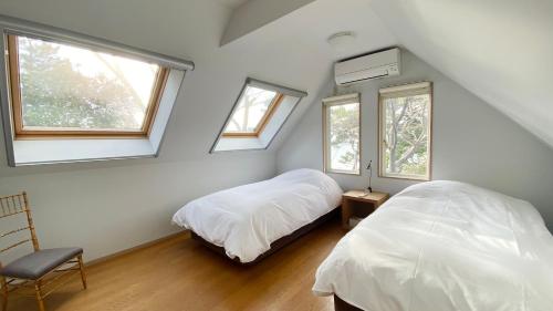 a bedroom with two beds and two windows at Hayama Isshiki Beach House -葉山 一色海岸の家 - ペット可 in Hayama