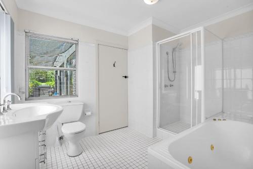 a white bathroom with a tub and a toilet and a sink at The Rotunda, Gerroa in Gerroa