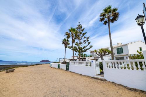 a white house on the beach with palm trees at Villa La Maja Beachfront in Corralejo