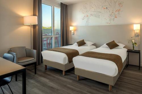 a hotel room with two beds and a chair at Citadines Montmartre Paris in Paris