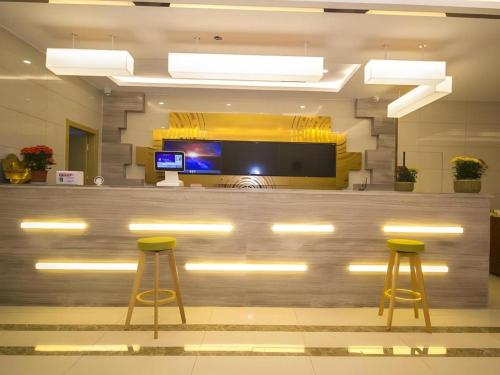 eine Lobby mit einer Bar mit zwei gelben Hockern in der Unterkunft GreenTree Inn Weifang Kuiwen District Beiwang Jiale in Weifang