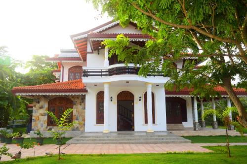 a large white house with a tree in front of it at Sri Lagoon Villa in Negombo