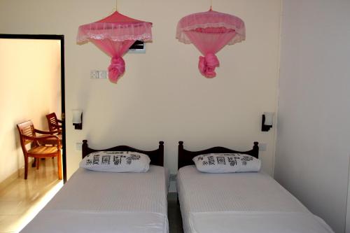 two beds in a room with pink curtains at Holiday Guest Inn in Negombo