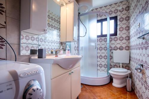 een badkamer met een wastafel, een toilet en een douche bij Apartments Nikola Vidović in Komiža