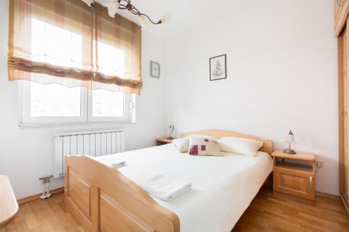 a bedroom with a bed with white sheets and two windows at Galileo Apartment in Zagreb