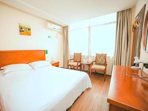 a hotel room with a bed and a table and chairs at GreenTree Inn Yangzhou Slender West Lake Wencheng Attic Express Hotel in Yangzhou
