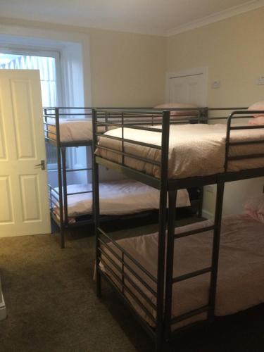Pokój z 3 łóżkami piętrowymi i drzwiami w obiekcie Edinburgh West Side Hostel w Edynburgu